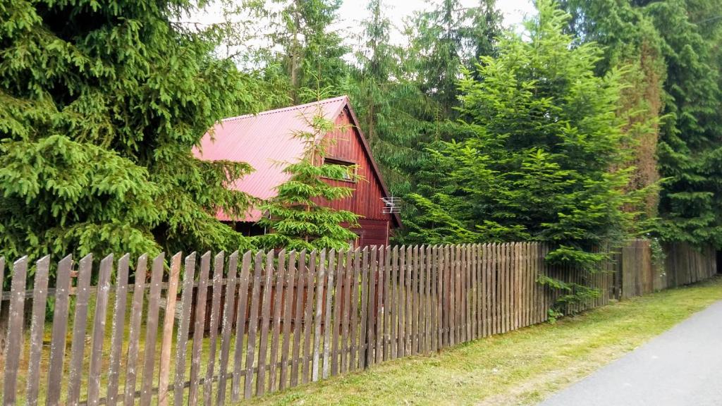 a fence next to a red house behind a fence at Chatka Nad Strumieniem in Glinka