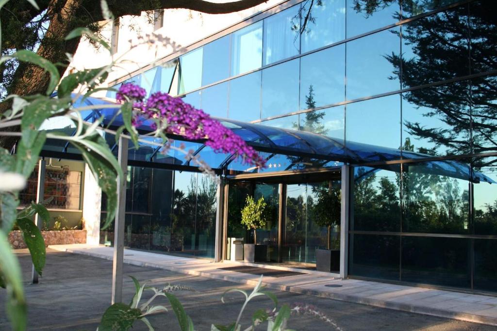 un gran edificio de cristal con flores púrpuras delante de él en Hosteria El Valles 2 ESTRELLAS, en Briviesca
