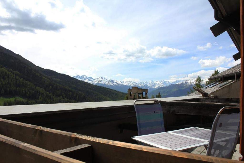 a table and chairs sitting on top of a roof with mountains at Residence Ciel Bleu - Fraz Pos in Aosta