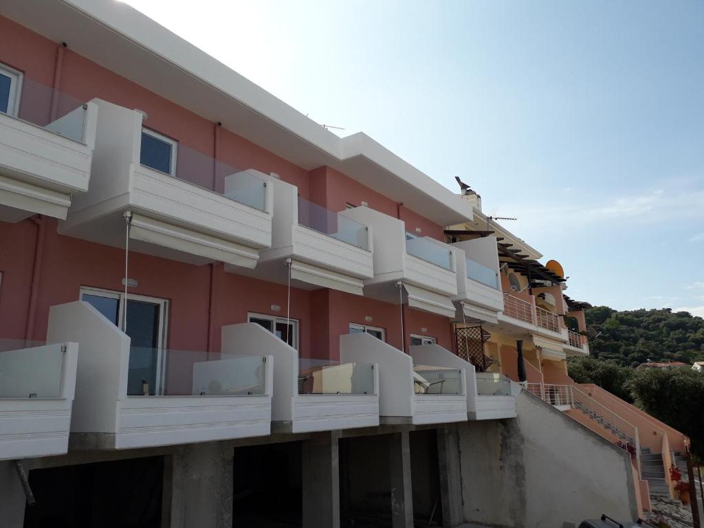 un edificio rojo con balcones blancos. en Sirakgast Ionian Sea Appartments, en Preveza