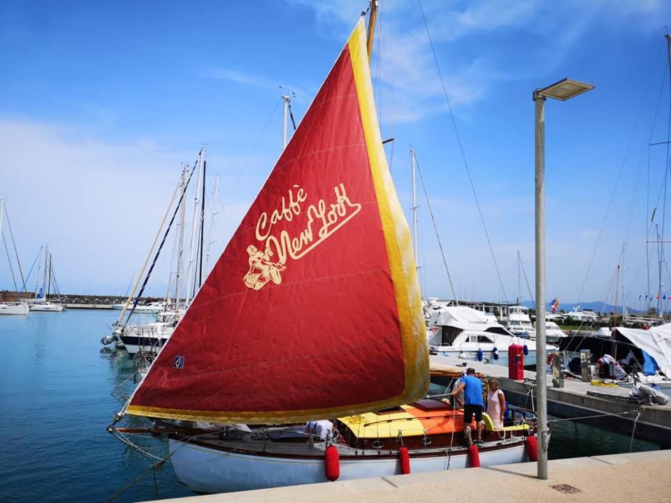 a boat with a red sail is docked at a marina at Margarethe in Marina di Pisa