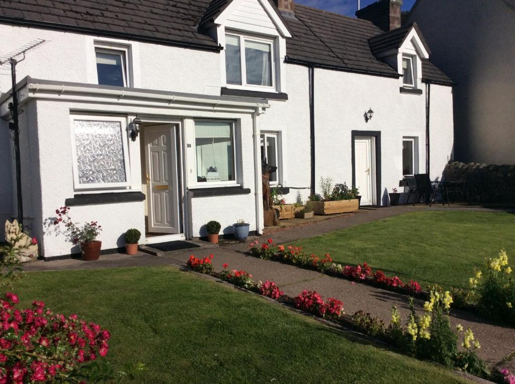 una casa blanca con un patio con flores en 28 Hillside, en Lochinver