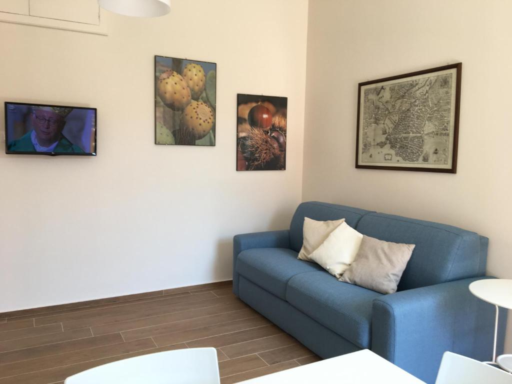 salon z niebieską kanapą i obrazami na ścianie w obiekcie A Casa di Clara w Syrakuzach