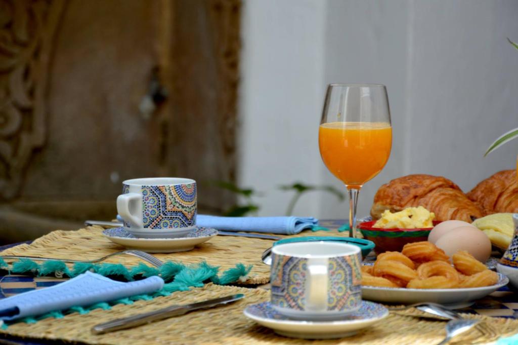 a table with a glass of orange juice and bread at RIAD OASIS D'ASILAH in Asilah