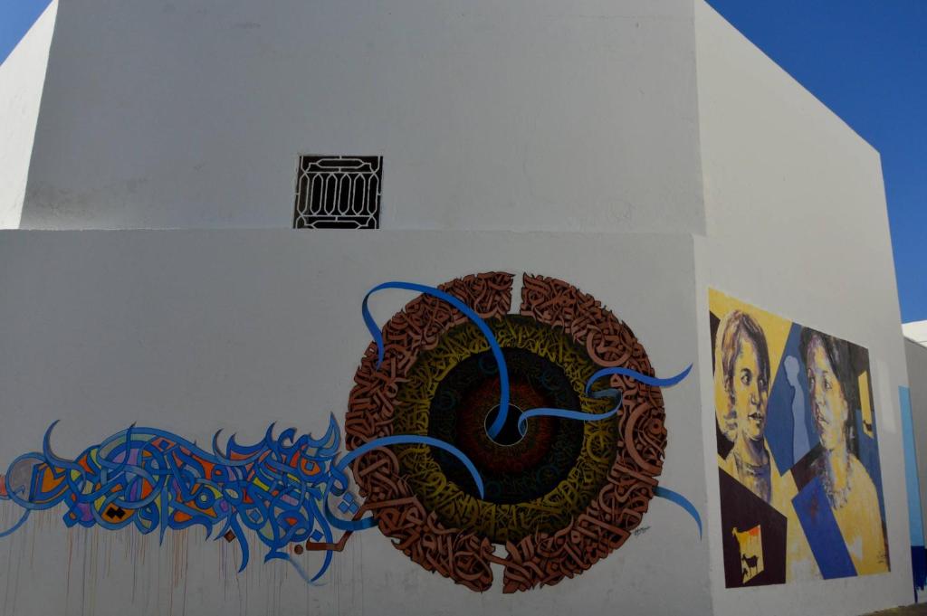 a wall with a painting on it next to some pictures at RIAD OASIS D'ASILAH in Asilah