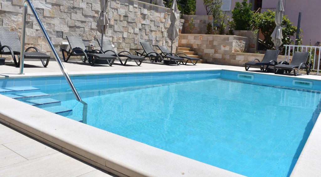 une grande piscine bleue avec des chaises et des tables dans l'établissement Marlin Apartments, à Dubrovnik