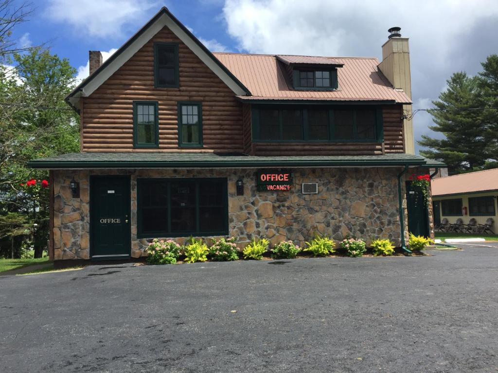 a house with a stone building with a garage at Pine Knoll Hotel Lakeside Lodge & Cabin in Old Forge