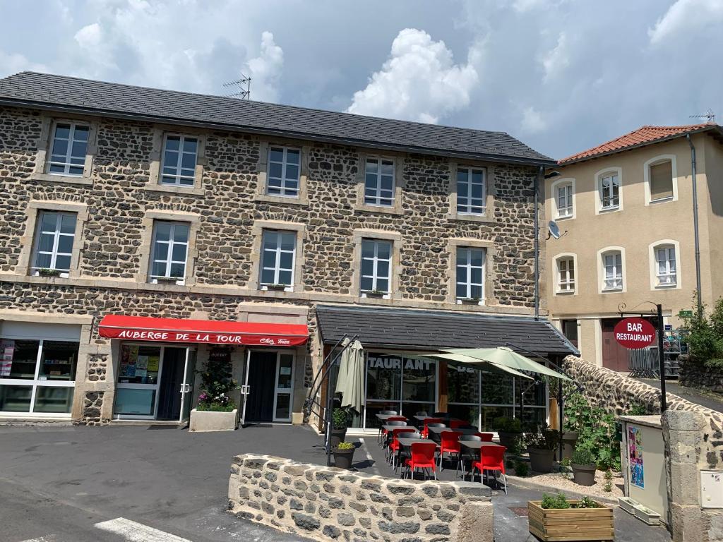 a large stone building with tables and chairs in front of it at Auberge de la Tour in Freycenet-la-Tour