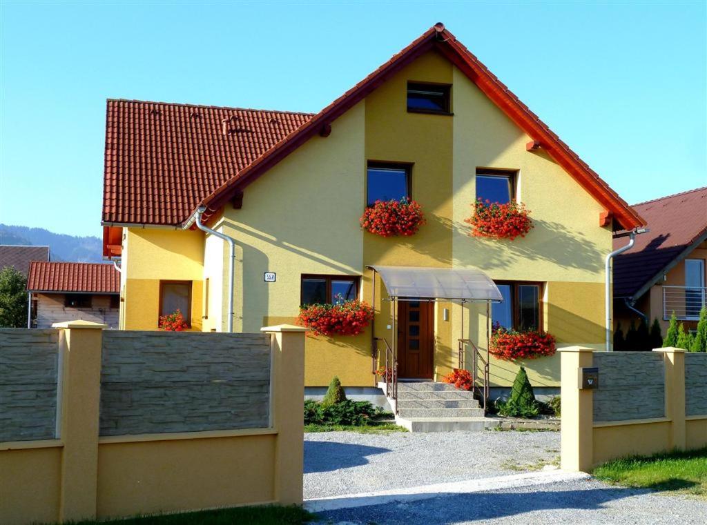 a yellow house with a fence in front of it at Apartmány Lýdia in Zuberec