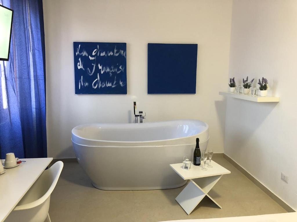 un bagno bianco con vasca e lavagna a muro di Les Chambres de Françoise Guest House a Olbia