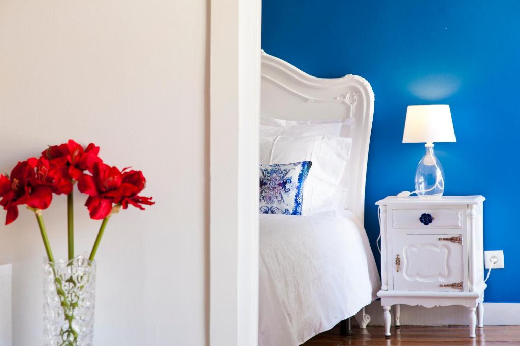 リスボンにあるBairrus Lisbon Apartments - Alfamaのベッドルーム1室(赤い花の花瓶付)