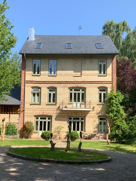 a large brick house with a tree in front of it at Waldmühle in Schleswig