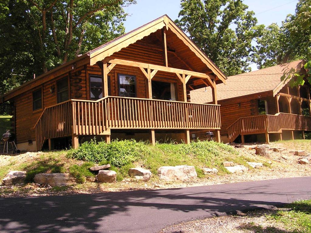 ein großes Holzhaus mit einer Veranda auf einem Hügel in der Unterkunft Mill Creek Resort on Table Rock Lake in Lampe