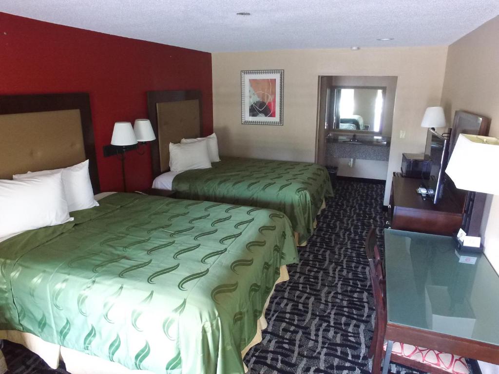 a hotel room with two beds with green sheets at Cross Road Motel in Trenton