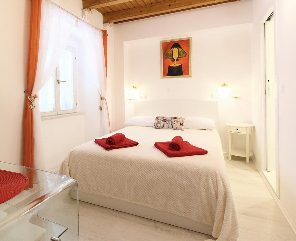 ドゥブロヴニクにあるAngelus Roomsの白いベッドルーム(ベッドに赤いタオル2枚付)