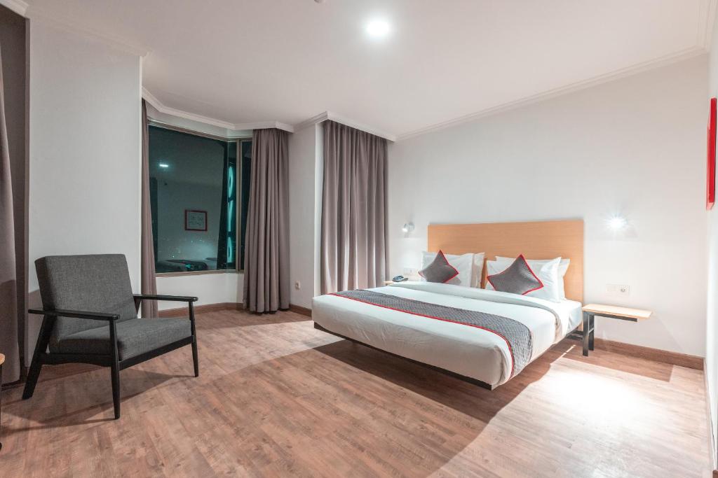 une chambre d'hôtel avec un lit et une chaise dans l'établissement OYO Townhouse 2 Hotel Gunung Sahari, à Jakarta