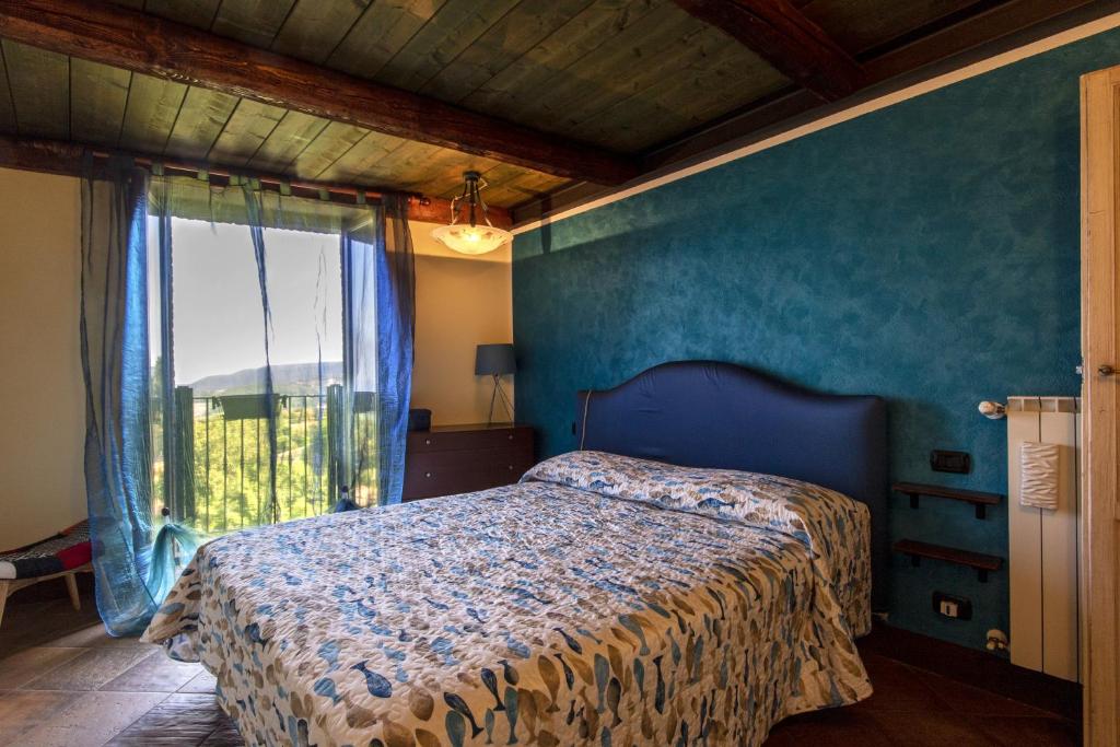 a bedroom with a bed with a blue wall and a window at Borgo Buio Town House in Montepulciano