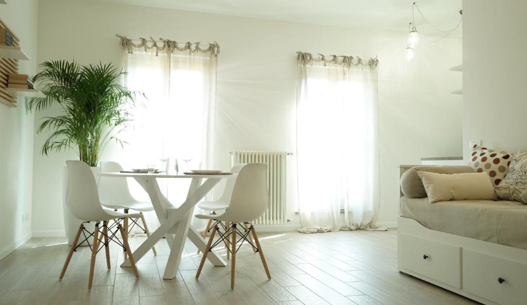 ein weißes Wohnzimmer mit einem Tisch und Stühlen in der Unterkunft Casa Sisu - Apartment in Bergamo