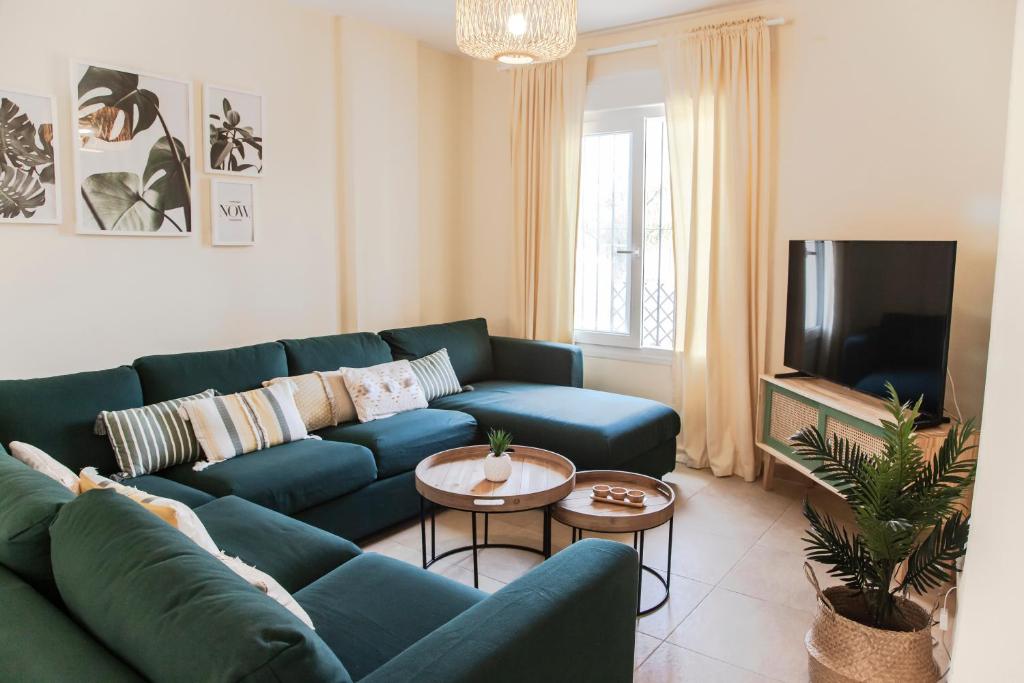 uma sala de estar com um sofá azul e uma televisão em Akutuna - Casa Familiar con Piscina , Garaje & Pista de Padel em Zahara de los Atunes