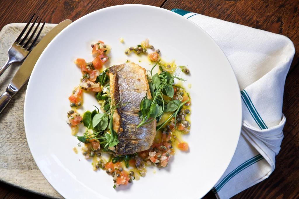 a plate of food with a piece of fish with vegetables at Victoria in Holkham