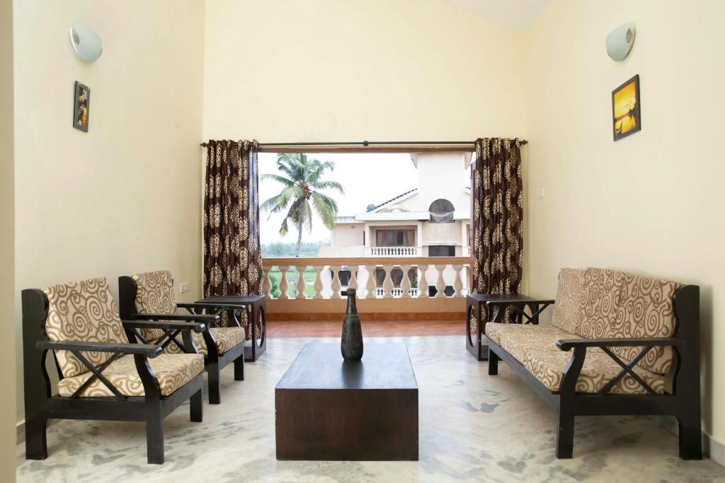 een woonkamer met stoelen en een vaas op een tafel bij Laxmi's Apartment - Coconut Grove Residence in Orlim