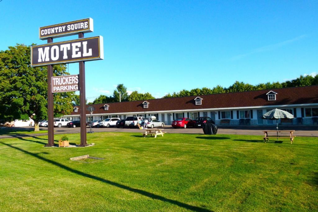 a motel sign in the grass in front of a building at Country Squire Motel in Arnprior
