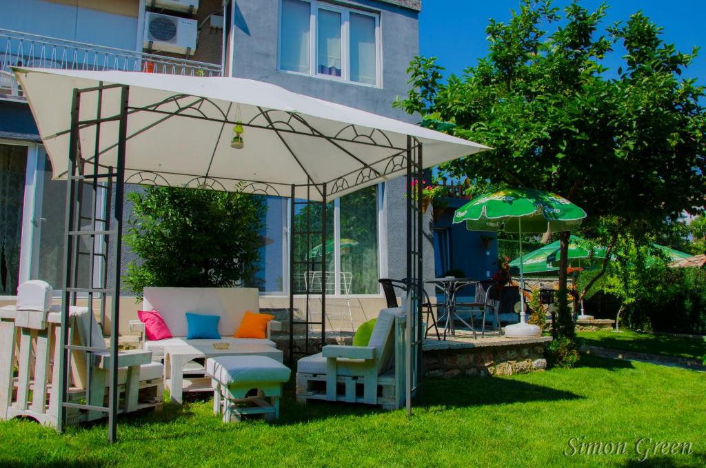 バルチクにあるGuest House Simon Greenの庭に椅子と傘を置いたパビリオン