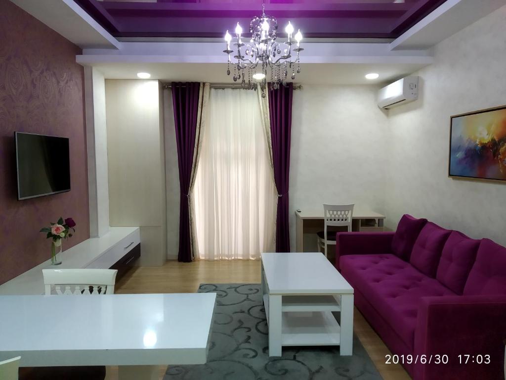 sala de estar con sofá púrpura y mesa en Green City Apartment 2, en Tashkent