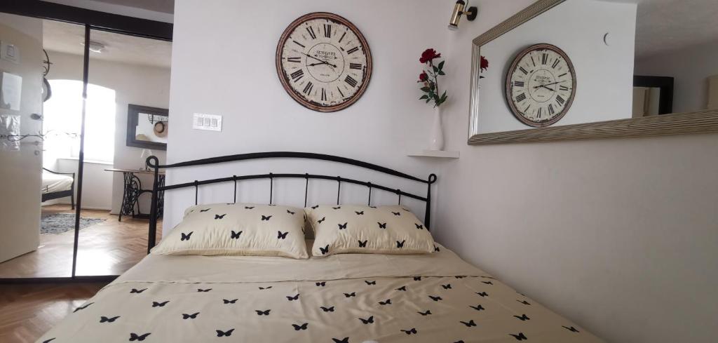 a bedroom with a bed with two clocks on the wall at Guest House Cittadella rooms in Dubrovnik