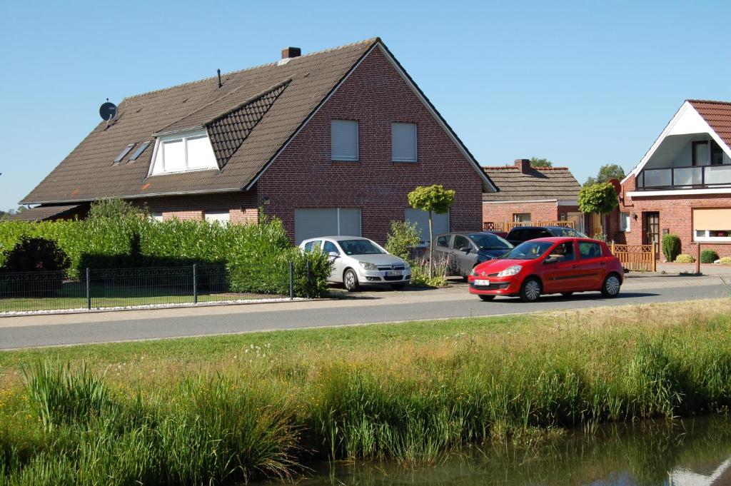 a house with cars parked on the side of the road at Ferienwohnung Wiekenblick in Wiesmoor