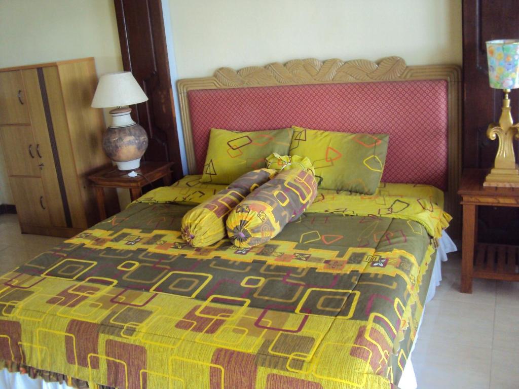 Una cama con una manta colorida y almohadas. en Teras Subak Jatiluwih, en Jatiluwih