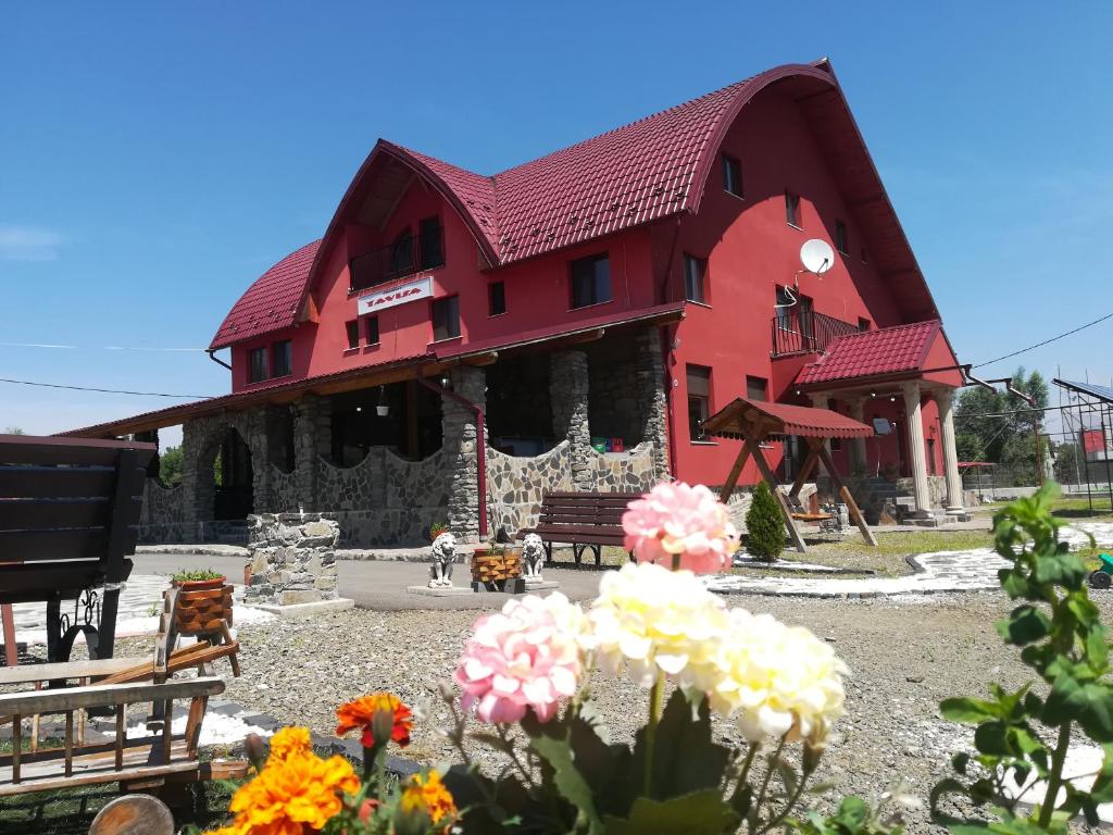 a red building with flowers in front of it at Pensiunea TAVISA in Sighetu Marmaţiei
