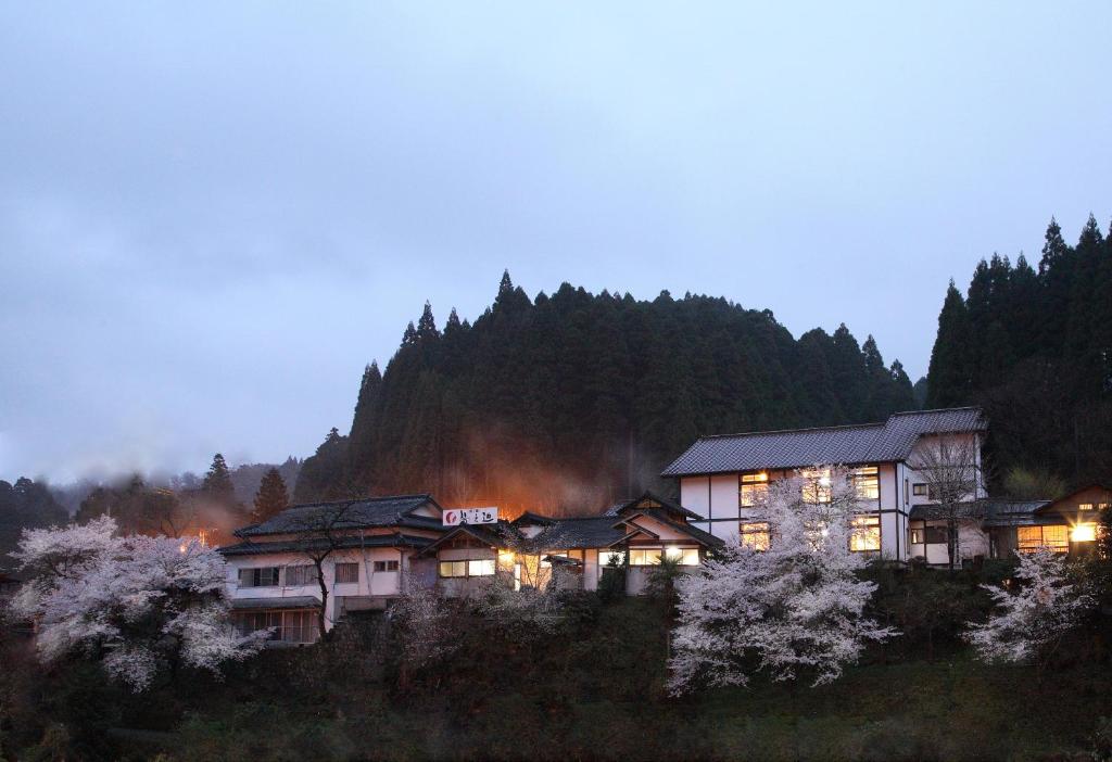 una casa en una colina con un fuego en el fondo en Ryokan Yunosako en Minamioguni