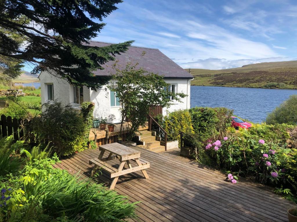 a house with a wooden deck next to a lake at Storr Apartments in Portree