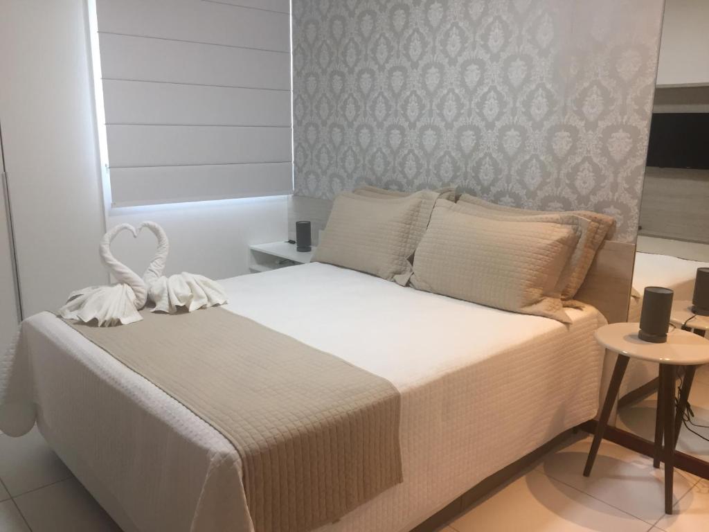 een slaapkamer met een groot wit bed en een tafel bij Apto Luxo Iloa Barra de São Miguel in Barra de São Miguel
