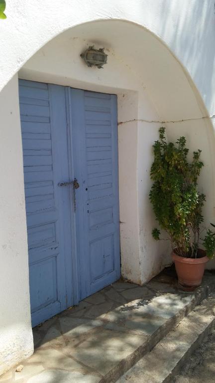 a blue door in a white building with a plant at The little bougainvillea house in Kýthira
