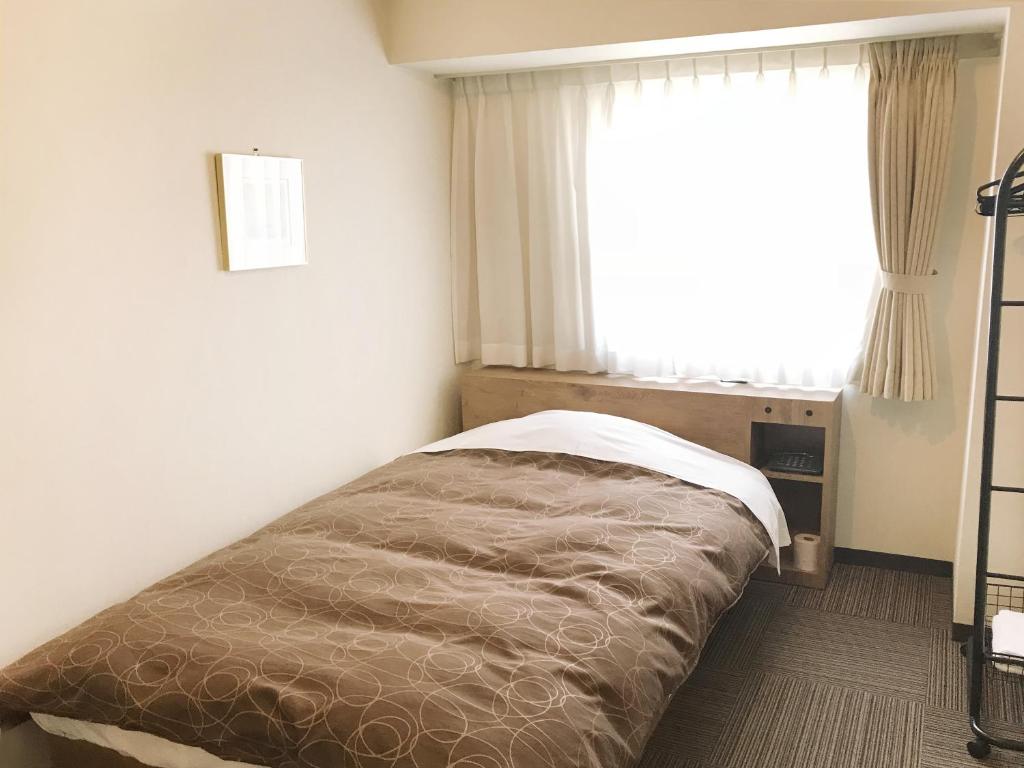 a bed in a bedroom with a large window at Ichinomiya Green Hotel in Ichinomiya