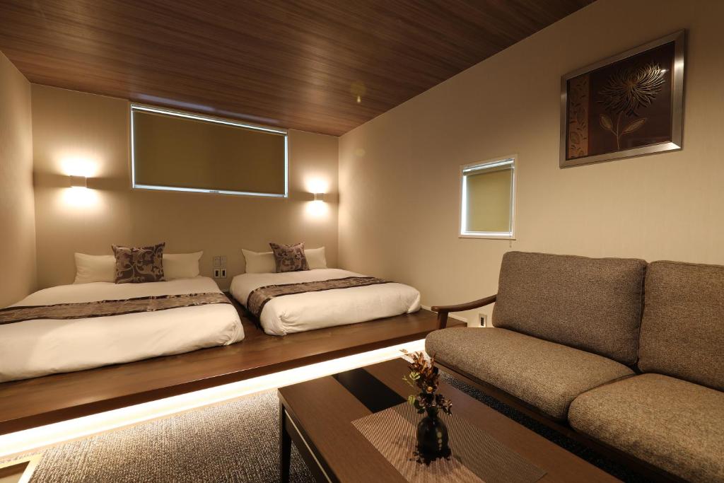 sala de estar con 2 camas y sofá en GRAND BASE Hakata City, en Fukuoka
