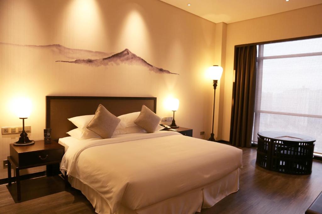 ein Schlafzimmer mit einem großen Bett mit einem Wandbild der Berge in der Unterkunft Amitabha Hotel (Fuzhou Pushang) in Fuzhou