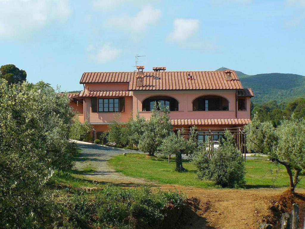 a large house with a yard with trees in front of it at Agriturismo De Santis in Castiglioncello