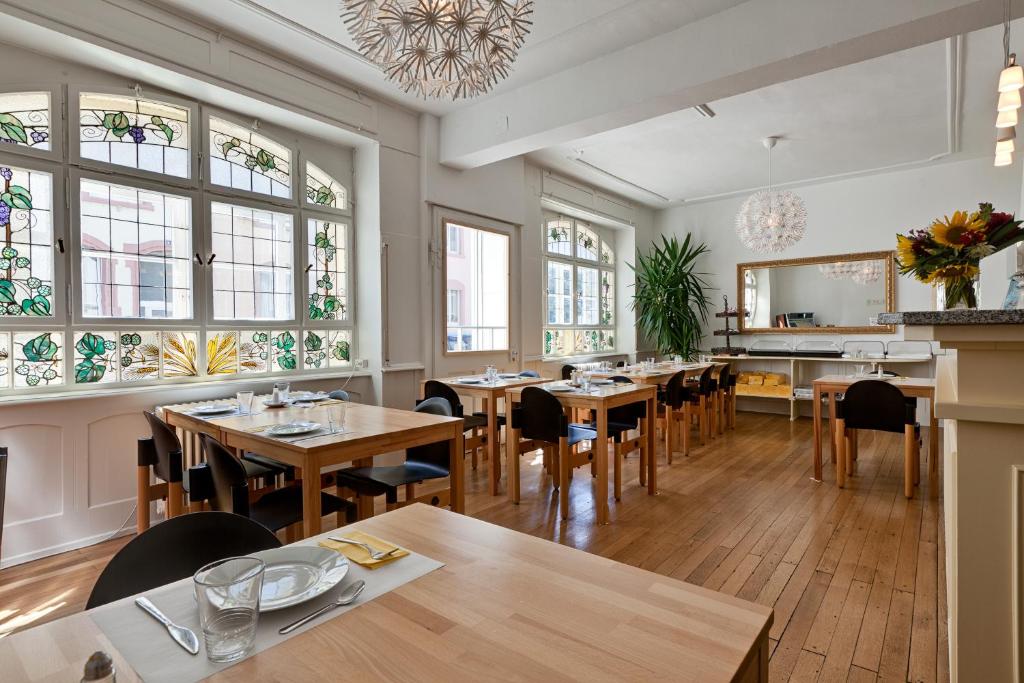 un ristorante con tavoli e sedie in legno e finestre di Pensionsieben Das andere Hotel a Lörrach