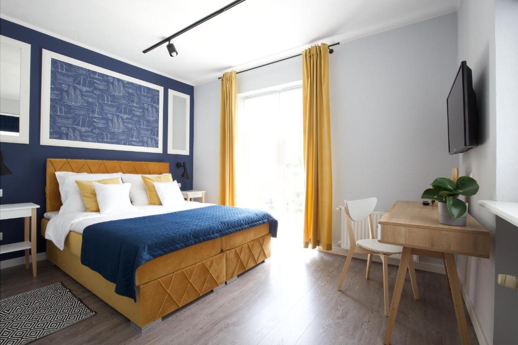 a bedroom with a bed with blue walls and a desk at Villa Orla in Gdynia