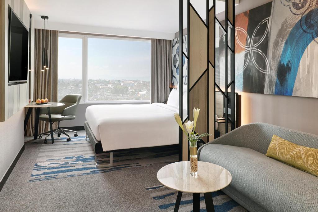 a hotel room with a bed and a couch at Novotel Suites Yogyakarta Malioboro in Yogyakarta