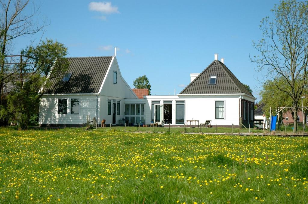 una casa blanca con un campo de flores amarillas en Amsterdam Farmland en Ámsterdam