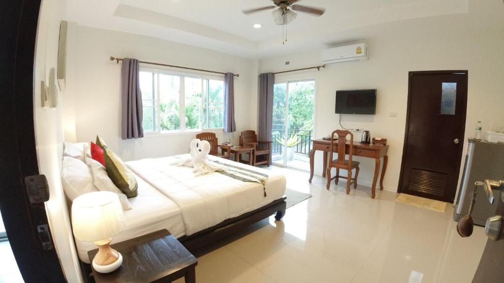 a bedroom with a bed and a living room with a table at Baan Glangsuan Bang Kobua in Bang Chak