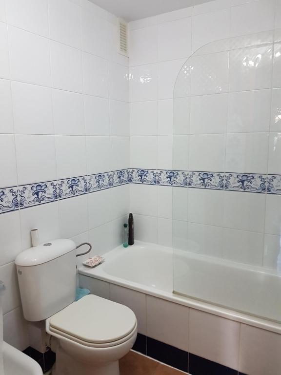 a white bathroom with a toilet and a bath tub at Apartamentos Atlanterra COSTA Y SOL in Zahara de los Atunes