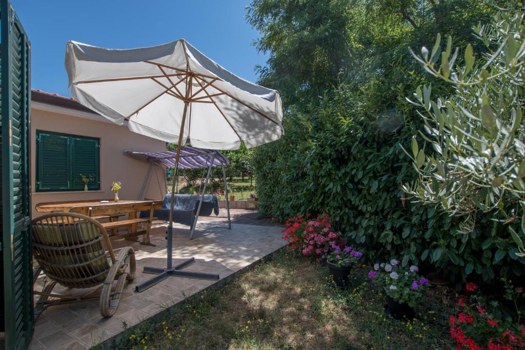 eine Terrasse mit einem Sonnenschirm, einem Tisch und Stühlen in der Unterkunft Holiday Home Suzana 1276 in Kaštel