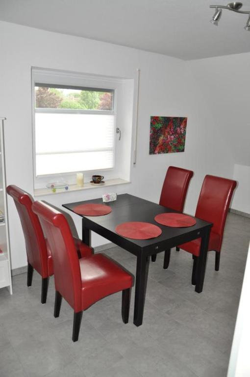 a dining room with a black table and red chairs at Ferienwohnung Kaplan in Bad Zwischenahn