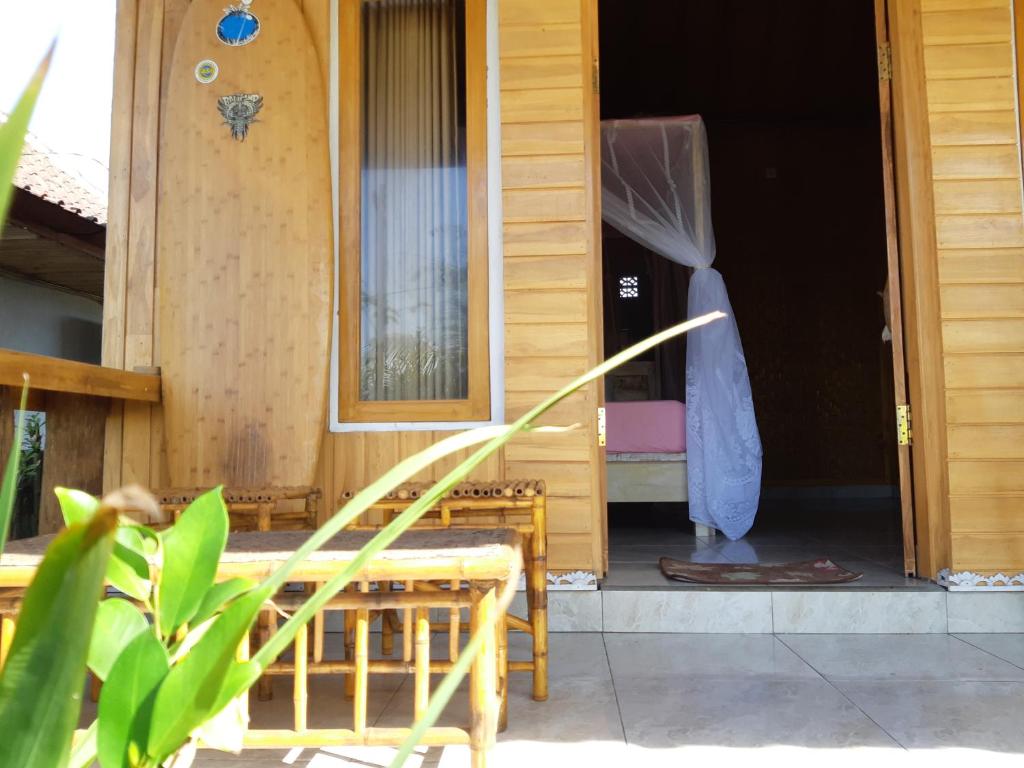 een open deur van een houten huis met een veranda bij Friend House SURF & STAY in Airsatang