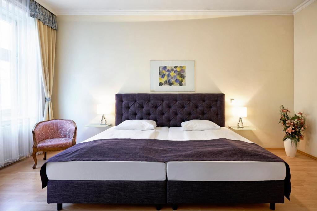 Apartments Deutschmeister في فيينا: غرفة نوم بسرير كبير وكرسي